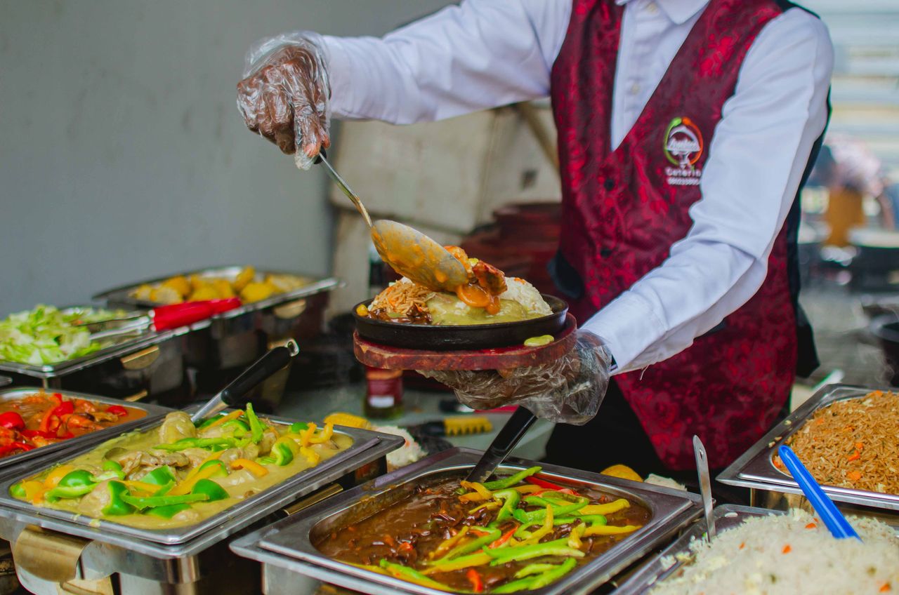 A chef expertly serves a variety of colorful dishes at a buffet, highlighting culinary expertise.