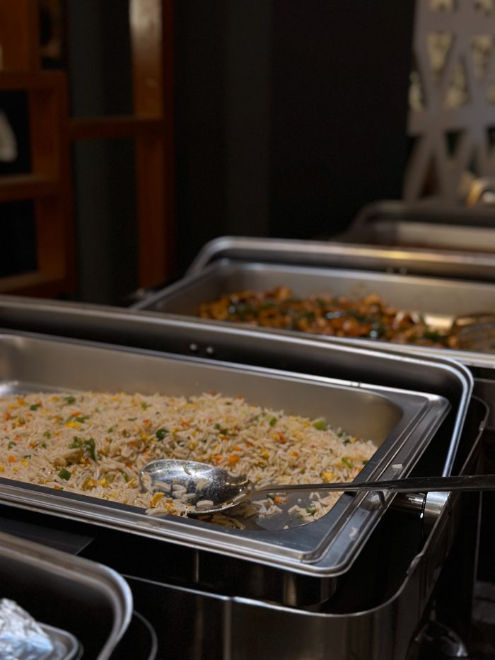 Services A close-up of buffet-style rice and vegetables served in catering trays, ready for guests.