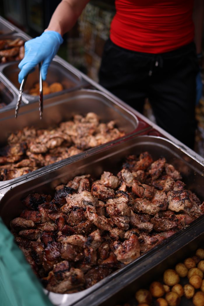 Services Close-up of grilled meat being served with tongs at a street food stall.