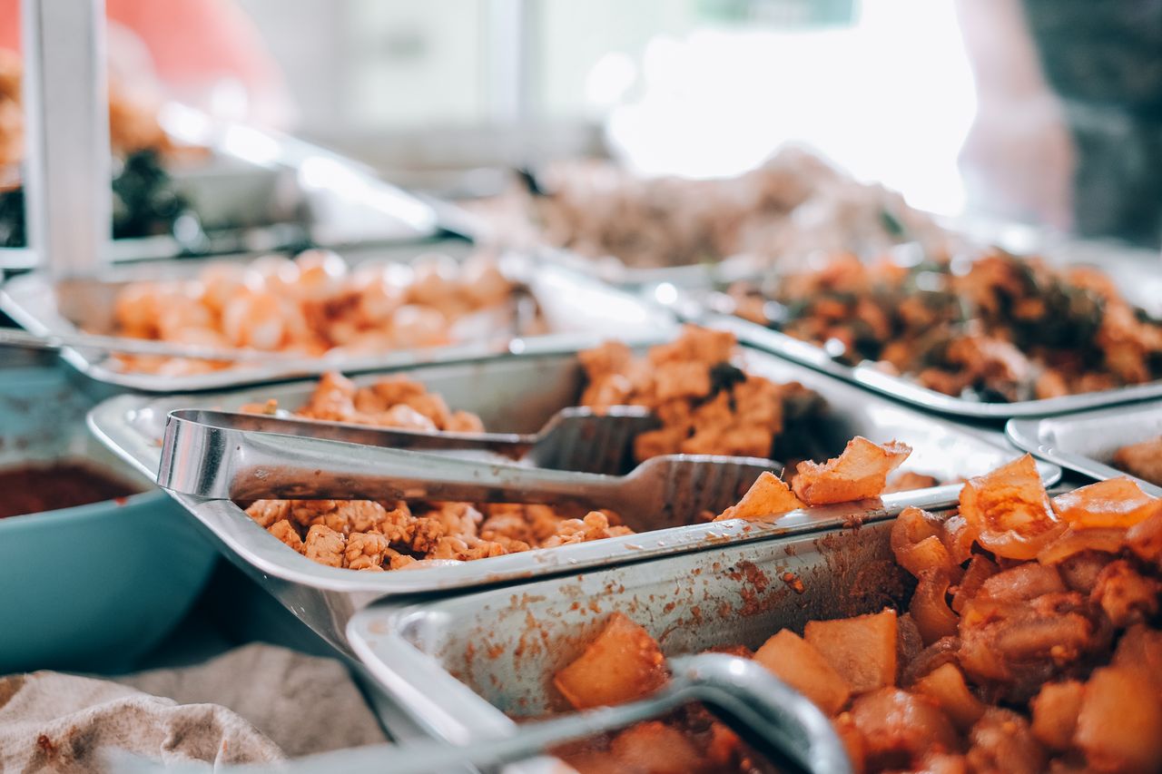 Services An inviting display of various hot buffet dishes in stainless steel trays, perfect for food enthusiasts.